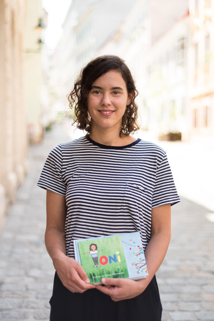 Portrait von Verena, der Autorin der TONI-Bücher, mit einem ihrer TONI-Bücher in der Hand.